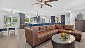 Ein modernes Wohnzimmer mit einem braunen Ledersofa, einem runden Couchtisch und einem Deckenventilator.