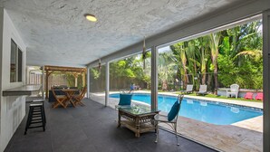 Ein großzügiger Innenbereich mit Glaswand und Blick auf einen Pool, ausgestattet mit Tischen und Stühlen.