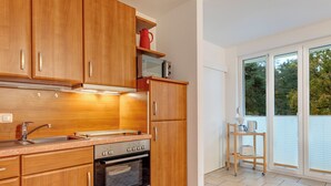 A modern kitchen with wooden cabinets, a Bosch oven, a microwave, and a small table with a kettle. - Haus Eichhorst, Whg. 03: Close to the sandy beach in Trassenheide (Trassenheide)