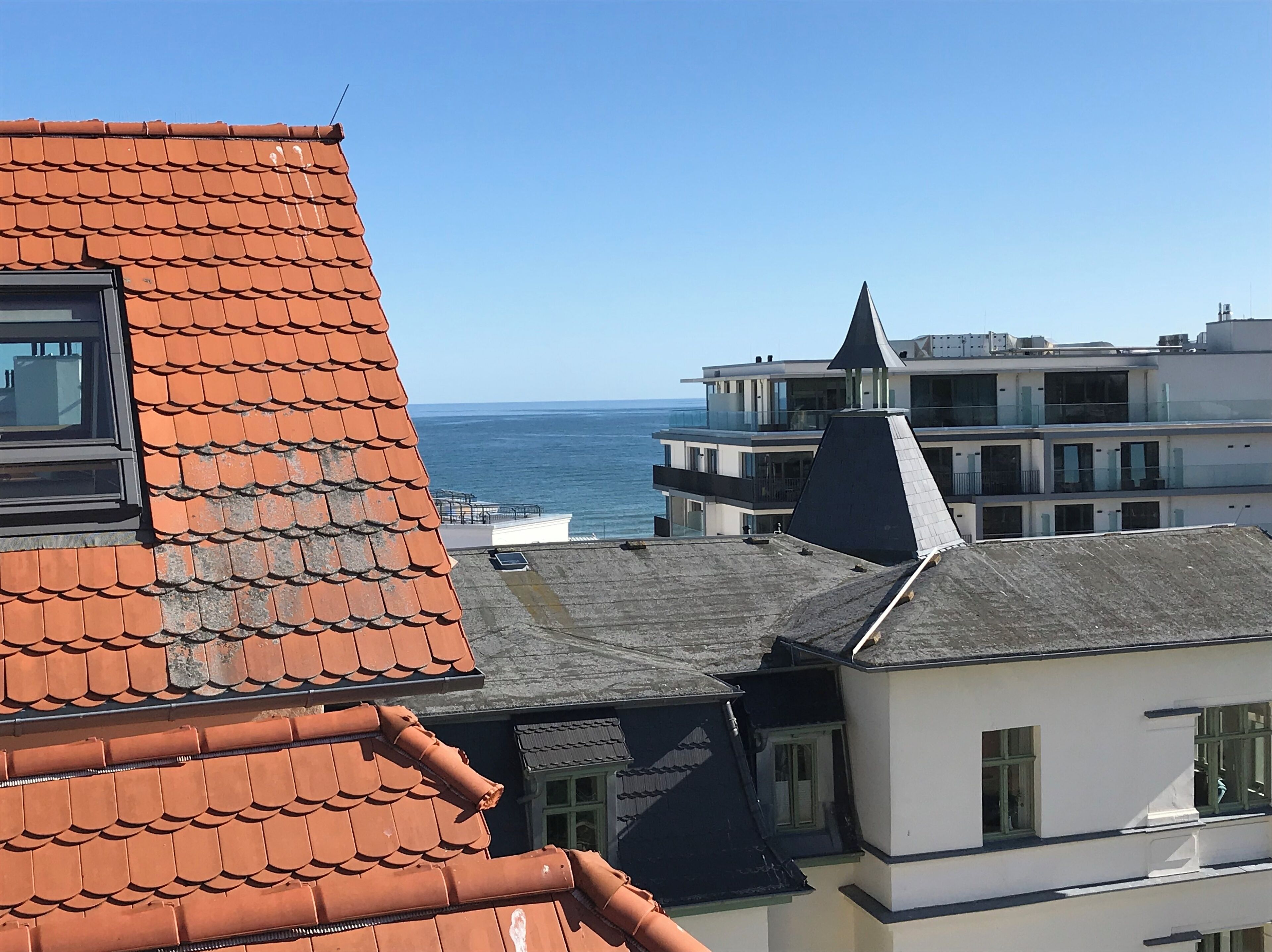 Ein Küstengebäude mit rotem Ziegeldach, weißer Fassade und Blick auf das Meer.