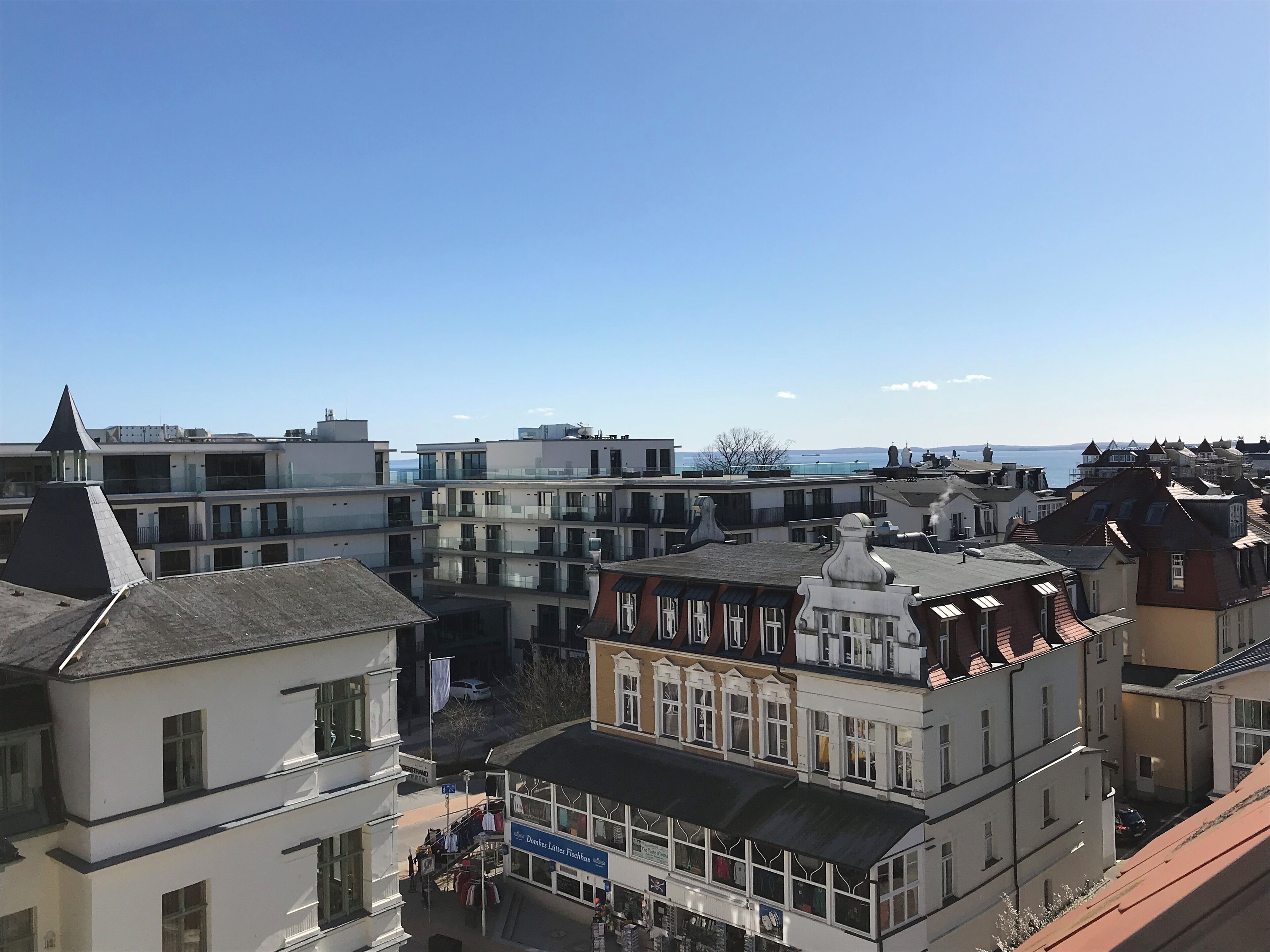 A multi-story building with a variety of architectural styles, including a prominent white building with a black roof and a smaller building with a red roof.