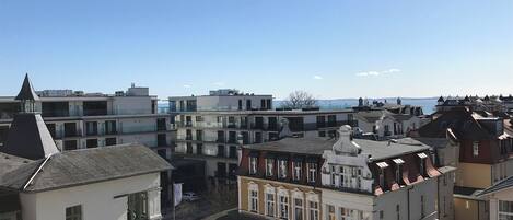 A multi-story building with a variety of architectural styles, including a prominent white building with a black roof and a smaller building with a red roof.