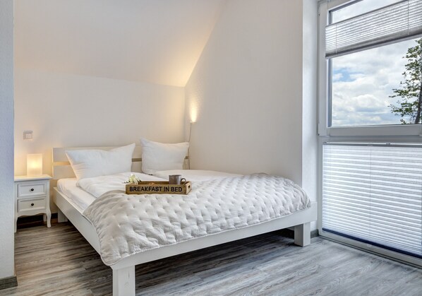 Une chambre à coucher avec un lit, une table de chevet et une fenêtre avec des stores.