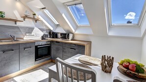 A modern kitchen with skylights, a built-in oven, and a dining area with a fruit bowl. - Emilia vacation apartment in Trassenheide: WiFi, garden & only 1.9 km to the beach (Trassenheide)