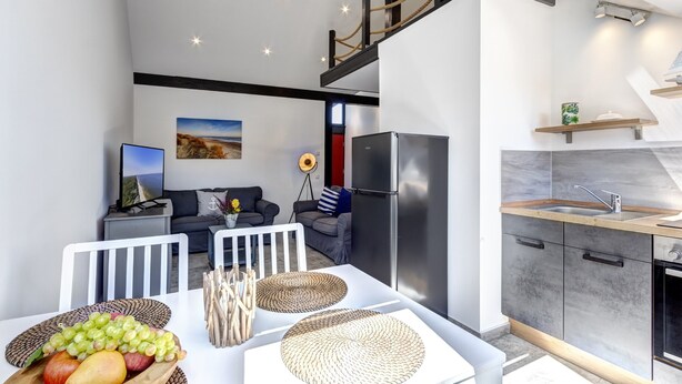 A modern kitchen with a built-in refrigerator and a wooden countertop. - Emilia vacation apartment in Trassenheide: WiFi, garden & only 1.9 km to the beach (Trassenheide)