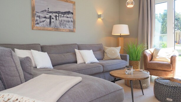 Un salon moderne avec un canapé gris, une table basse ronde, une lampe et un tableau encadré accroché au mur.