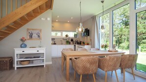 Une cuisine moderne avec de grandes fenêtres, une table à manger en bois et un escalier.