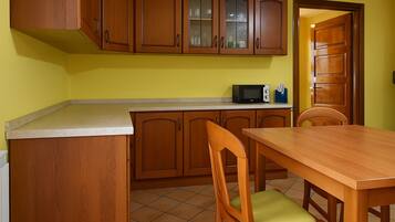 Una cocina con armarios de madera, microondas y una mesa de comedor con sillas.