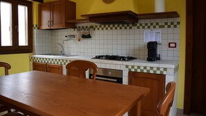 Eine Küche mit einem Holztisch, Stühlen, einem Herd, einer Spüle und einer Kaffeemaschine.