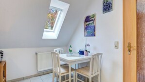 A small, well-lit room with a slanted skylight, a white table with chairs, a radiator, and a wooden door. - Hansehus, Whg. 5: close to the beach in Zinnowitz with balcony and WLAN (Zinnowitz)