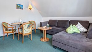 Een gezellige woonkamer met een bank, twee fauteuils, een klein rond tafeltje en een wandlamp.