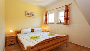 Quarto com cama de madeira, duas mesas de cabeceira com luminárias, janela com cortinas e um quadro na parede.