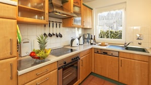 Uma cozinha moderna com armários de madeira, fogão de aço inoxidável e janela que traz luz natural.