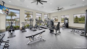 A gym with various exercise equipment, large windows, and a ceiling fan. - 10251 Ebb Tide Lane (Orlando)
