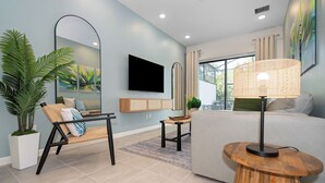 A modern living room with a sofa, a coffee table, a TV, and a large mirror. - 10251 Ebb Tide Lane (Orlando)