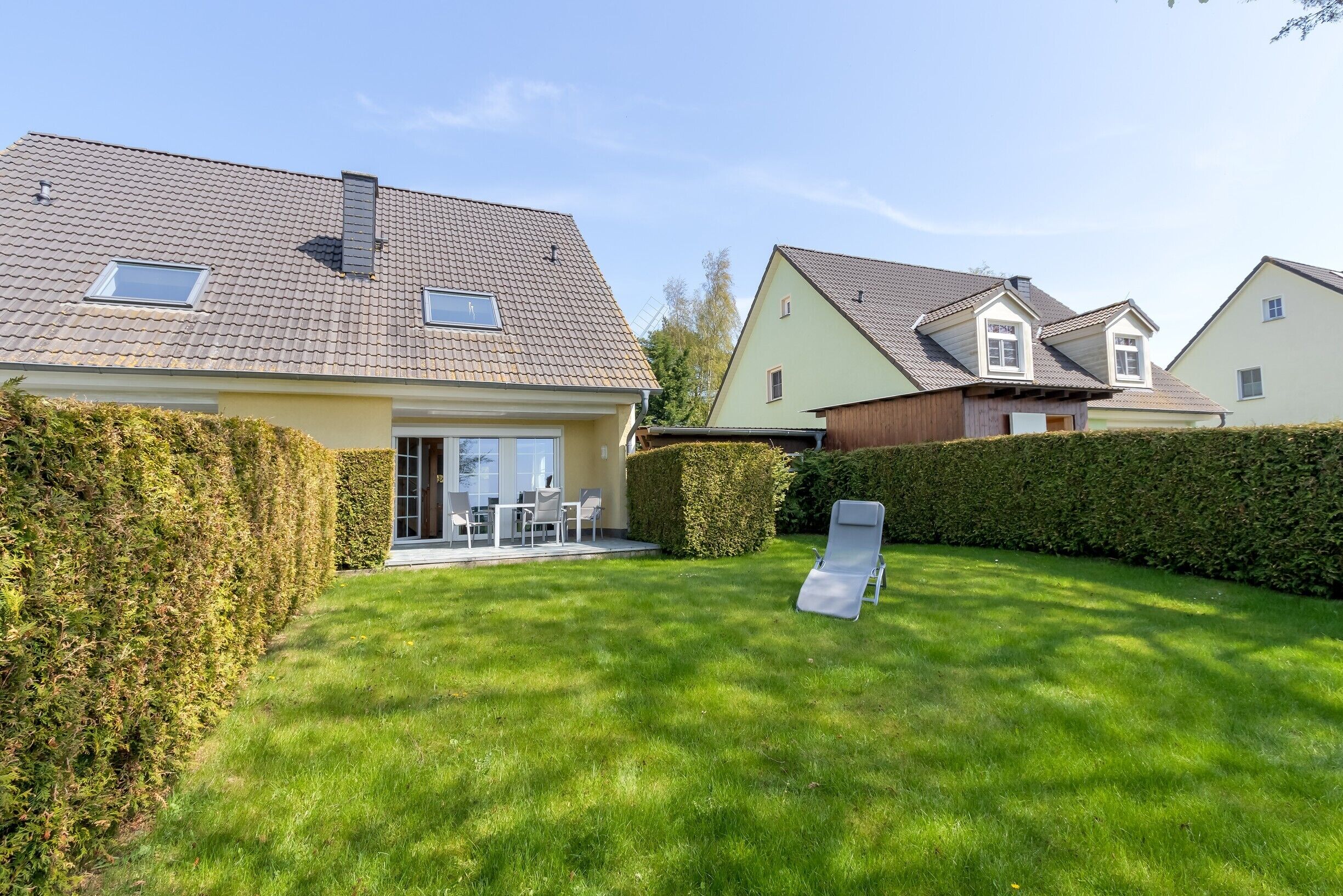 A residential property with a well-maintained lawn, a patio with outdoor furniture, and a sliding glass door leading to a covered area.