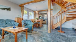 Un vaste salon agrémenté d’un escalier en bois, un coin repas et une cuisine à l’arrière-plan.