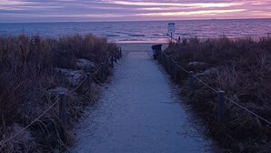 A pathway leading to the beach with a signboard visible in the distance.