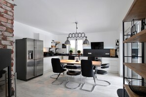 Enjoy cooking in this kitchen with a stainless steel refrigerator, dining table, and pendant light fixture.