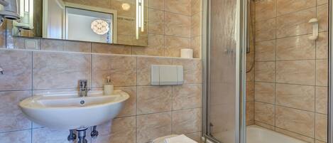 Un baño con lavamanos, inodoro y ducha.