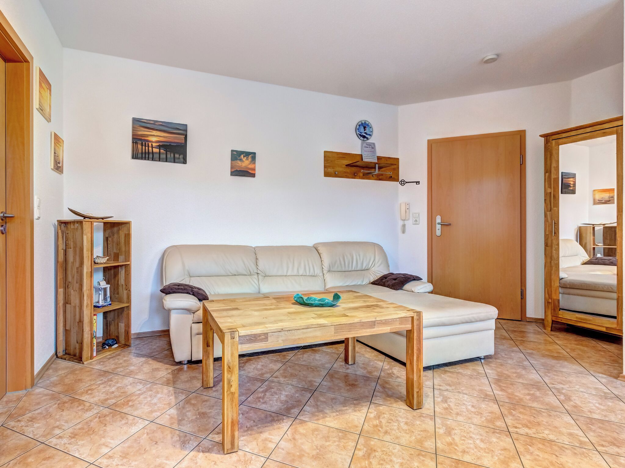 Een woonkamer met een beige bank, een houten salontafel en een houten kast.