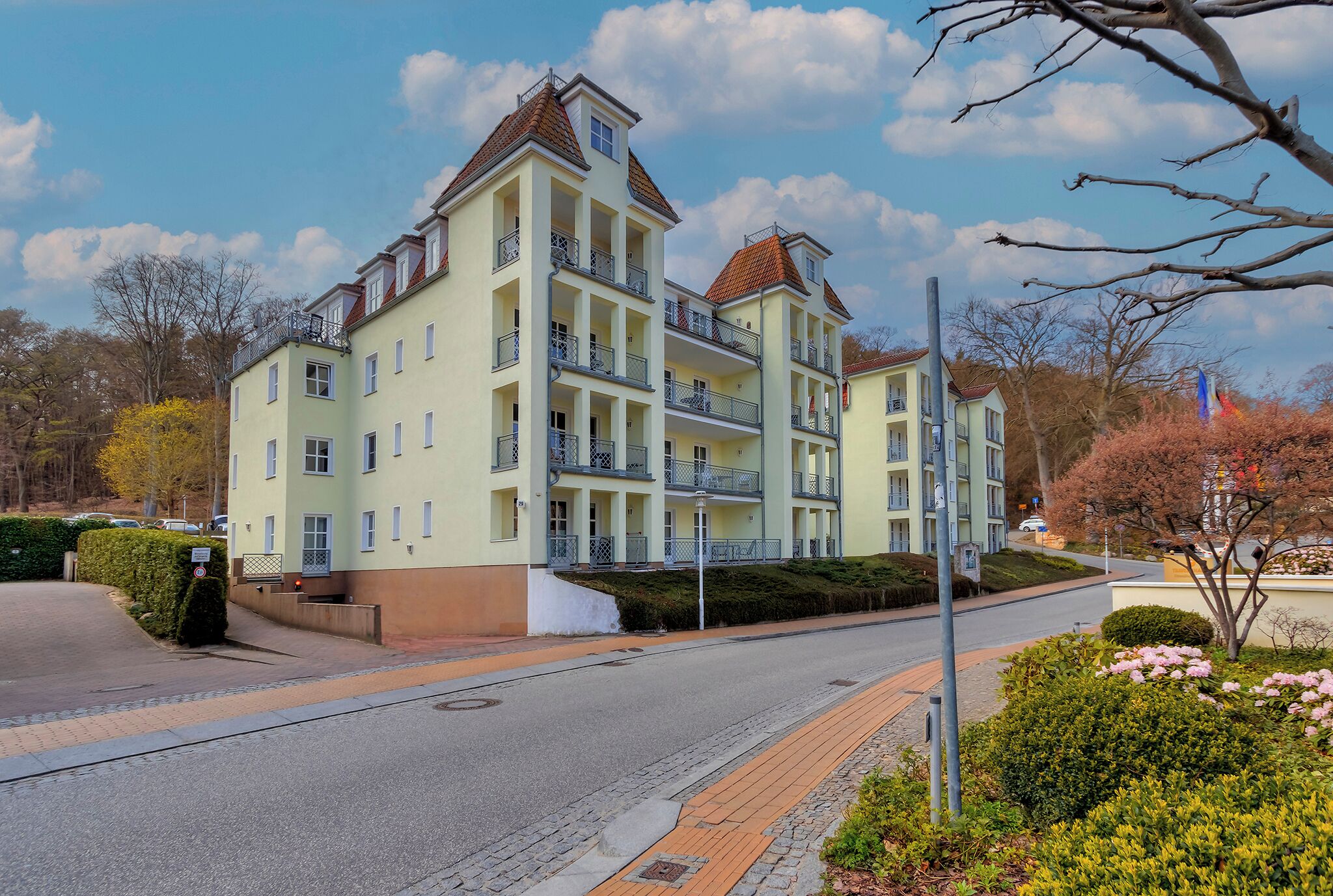 A multi-story hotel with balconies, a paved driveway, and a landscaped garden.