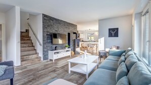 Una sala de estar moderna con escalera, comedor y cocina.