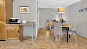 Eine moderne Küche mit Mikrowelle, Toaster und Holzschränken. Ein Essbereich mit Tisch, Stühlen und einer Pendelleuchte.