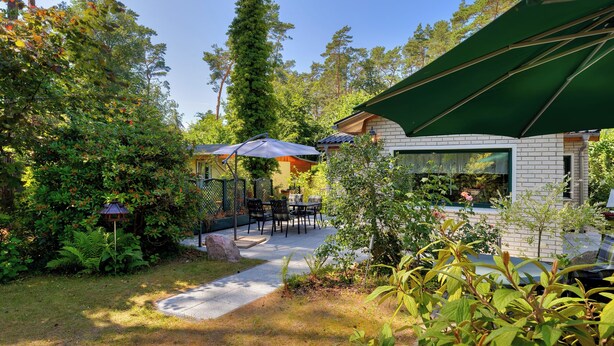 Ein Patio mit Sitzgelegenheiten im Freien, ein Backsteinhaus und ein grüner Sonnenschirm.