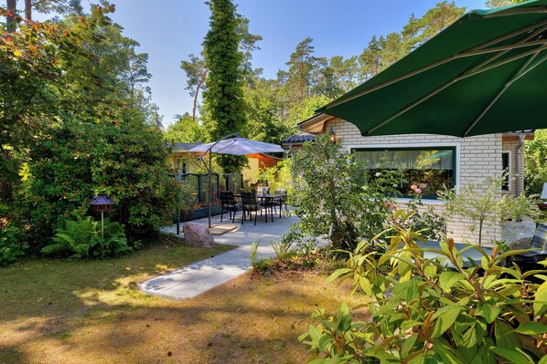 A patio area with outdoor seating, a brick building, and a green umbrella.