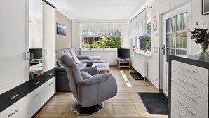 Eine moderne Küche mit Einbauofen, ein Essbereich mit grauem Sofa und Blick auf Grünfläche.
