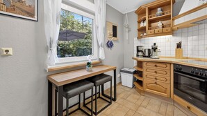 Eine kleine Küche mit Holzarbeitsplatte, einem eingebauten Backofen und einem Fenster mit Blick auf Grünflächen.