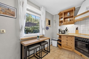 A compact kitchen with a wooden countertop, a built-in oven, and a window with a view of greenery.