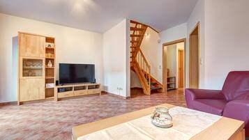 Ein Wohnzimmer mit einem Fernsehmöbel aus Holz, einer Couch und einer Treppe.