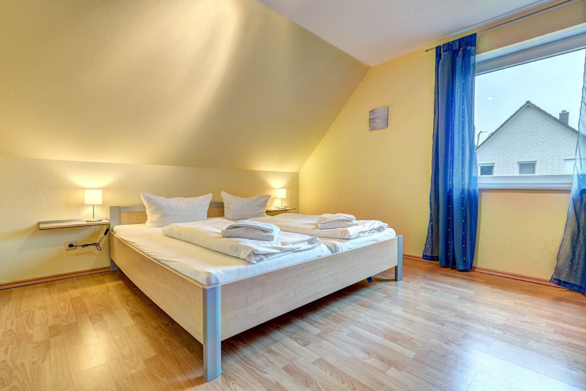 Ein Schlafzimmer mit einem Bett, Nachttischen und einem Fenster mit Vorhängen.