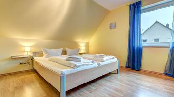Ein Schlafzimmer mit einem Bett, Nachttischen und einem Fenster mit Vorhängen.