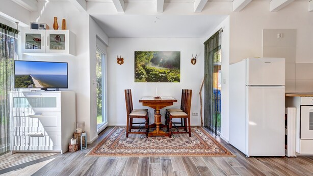 A modern kitchen with a dining area, large windows, and a view of the outdoors. - Vacation home Schwalbennest with terrace, WLAN and close to the sandy beach in Kölpinsee (Kölpinsee)