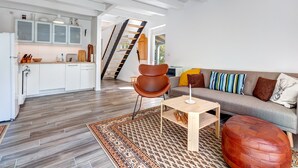 A modern kitchen with white cabinets, a wooden floor, and a staircase leading to an upper level. - Vacation home Schwalbennest with terrace, WLAN and close to the sandy beach in Kölpinsee (Kölpinsee)