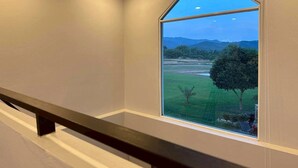 A room with a large window offering a view of a green landscape and mountains. - Naoat Resort Farm & Cafe (Mae Taeng)