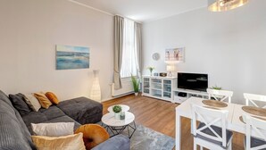 Uma sala de estar moderna com sofá, mesa de centro, TV e área de jantar.