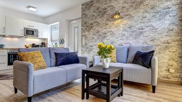 Ein modernes Wohnzimmer mit zwei grauen Sofas, einem kleinen dunklen Holztisch und einer Steinwand.