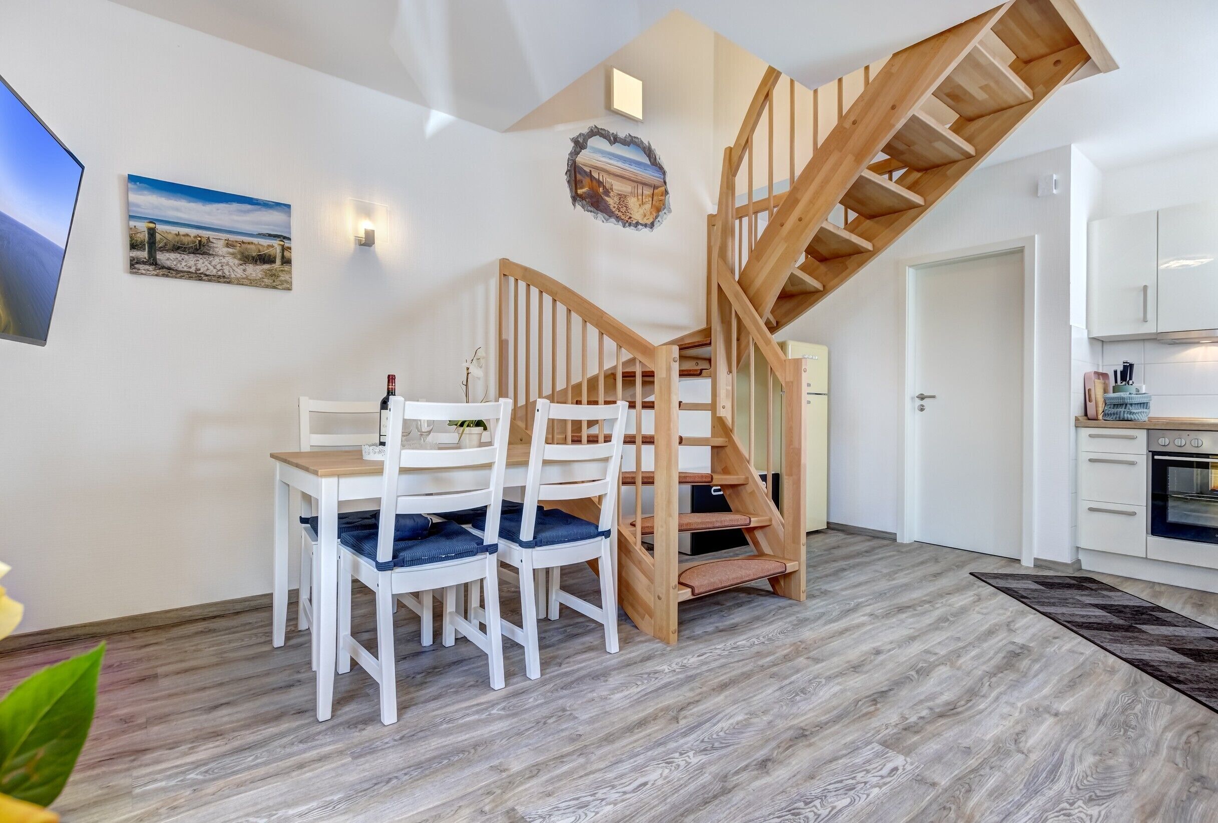 Ein modernes Interieur mit Essbereich, Holztreppe und Küche.