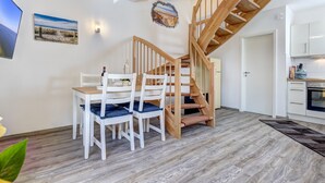 A modern interior with a dining area, wooden staircase, and kitchen.