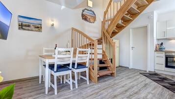 Ein modernes Interieur mit Essbereich, Holztreppe und Küche.