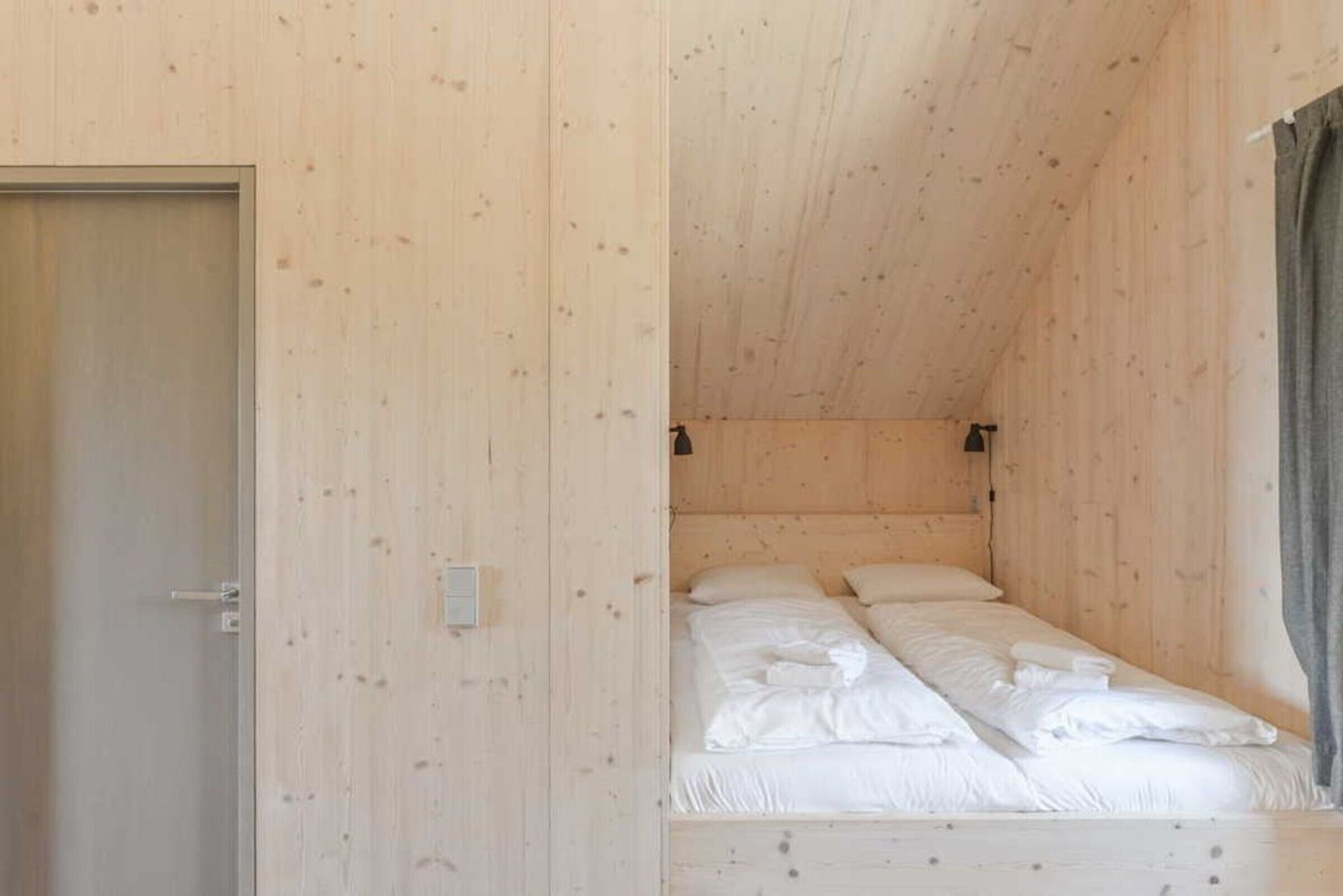 A single bed in a room with wooden walls and a sloped ceiling.