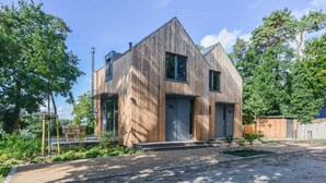 A modern two-story house with a wooden exterior, a front porch, and a small garden area. - "Söt Mine" Seaside Cottage – a stylish retreat on the Baltic Sea for up to 7 people (Loddin OT Stubbenfelde)