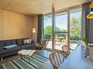 A modern living room with a sofa, chairs, a dining table, and a view through large windows. - "Söt Mine" Seaside Cottage – a stylish retreat on the Baltic Sea for up to 7 people (Loddin OT Stubbenfelde)