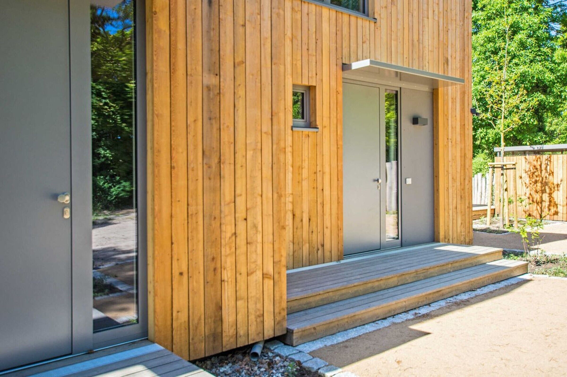 A modern wooden building with a glass door and a small window.