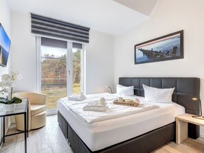 Relax in comfort with a large bed, glass desk, and wall-mounted TV.