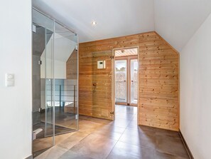 Spacious interior with a high ceiling, glass partition, and wooden door frame.